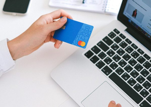 Person making an online purchase with a credit card on a laptop, showcasing modern ecommerce technology.